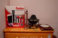 Realine fruit juicer box, glass bubble thermometer, tabletop fountain, and wall barometer on wooden dresser.