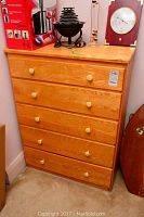 Front view of wood dresser with five drawers and round wooden knobs, showing natural wood grain and light wear.