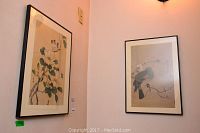 Photo of two framed Asian-style bird prints hung on walls, showing overall size and frame style.