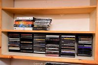 Multiple shelves displaying a large collection of PC game CD-ROM cases and jewel cases arranged in stacks and rows.