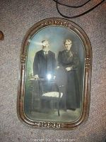 Close-up of vintage oval-framed black and white photograph of elderly man and woman