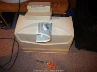 View of the Imperial Household Sewing Machine Model 919 in its white hard plastic carrying case with manual on top, placed on carpeted floor next to a pair of scissors