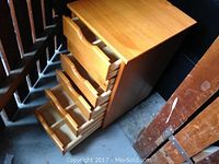 Wooden storage cabinet showing six open drawers with divider compartments inside, highlighting the internal structure and drawer depth.
