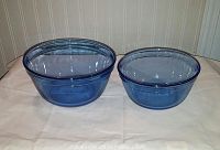 Two cobalt blue glass nesting ovenware bowls shown side by side on white cloth background. Shown from top angle to show shape and color.