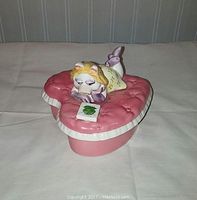 Ceramic trinket box showing Miss Piggy lying on pink heart-shaped cushion reading a book with Kermit the Frog on cover.