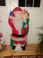 Front view of vintage lighted plastic Santa Claus figure, showing full body, suit details, and face clearly. Bright colors with red, white, green, and blue tones. Shows the teddy bear in sack detail.
