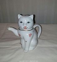 Front view of vintage white cat teapot with hand painted face and floral decoration