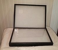 Open glass top display case showing the inside padding and cardboard sides