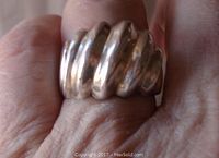Close-up view of the ring worn on a finger showing the dome and ribbed grooved design in polished sterling silver.