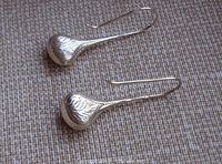 Pair of vintage sterling silver pierced earrings with engraved floral designs laid out on fabric.