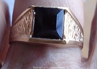 Close-up photo of the ring top showing square faceted black onyx stone and textured gold on band sides.
