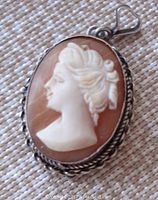 Front view of oval shell cameo pendant showing a left-facing lady's profile and twisted silver frame.