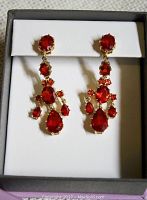 Photo showing a pair of red dangly statement earrings in a gift box, displaying the detailed design, size, and color.