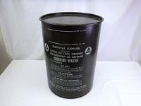 Front view of black metal barrel with white survival supply stenciling from US Office of Civil Defense - Department of Defense. Marked for 17.5 gallons drinking water capacity with instructions.