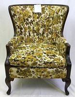Front view of vintage wingback armchair showing floral upholstery and wooden frame with cabriole legs.