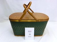 Front view of the picnic basket showing woven body and wooden top with vertical handles folded.