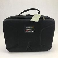 Front view of black fabric briefcase showing Johnnie Walker logo embossed at lower center and stitched logo patch with Vodafone McLaren Mercedes branding at upper center, with original tag attached to handle.