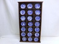 Full view of wooden display shelf holding all 21 blue and white Royal Copenhagen nursery rhyme plates arranged in rows.