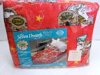 View of the sealed Disney Seven Dwarfs blanket in original packaging featuring red fabric with cartoon dwarf house prints and branding.