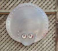 Front view of large round metal face sculpture with mirrored eyes and perimeter bulbs