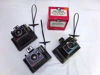 Photo showing the three Polaroid cameras and the Kali-Copier box arranged on a white surface.