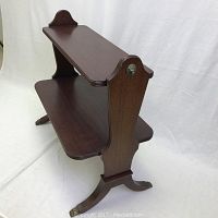 Two tier wooden side table angled view showing the top and lower shelves, brass lion head accents, and claw feet.