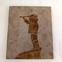 Top view of the marble tablet showing the etched Inuit figure playing a flute or pipe on a rocky base.