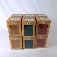 Stack of 6 tiki mugs in original boxes in three colors: light brown, dark green, and red.
