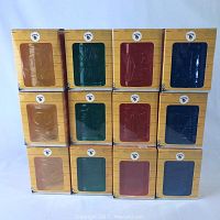 Stack of 12 Malibu Rum tiki glasses in original packaging arranged in 3 columns and 4 rows showing different colored glasses and box fronts.