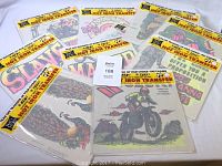Ten sealed iron-on transfer sheets laid out, showing the colorful 1970s artwork and packaging by Rat's Hole Daytona Beach.