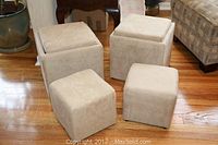 Four beige fabric storage ottomans grouped together on wooden floor.