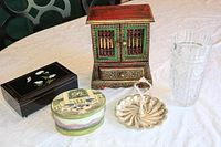 Overview photo showing entire lot on white table, including Indonesian jewel box, crystal vase, black lacquer box, ceramic candy dish, silver swan dish.