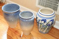 Three vases placed on wooden floor showing size and design contrast: two blue gradient and one floral decorated vase