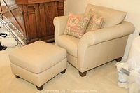 Full view of beige Italsofa leather armchair and matching ottoman on carpet, with two decorative pillows on chair seat.
