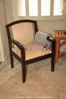 Full view of suede side chair with wood frame and wool throw draped on the armrest.