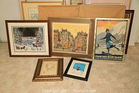 Five original framed artworks displayed together on floor against wall, showing variety of styles and sizes