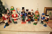 Full grouping of 13 wooden nutcrackers arranged on carpeted surface.