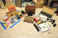 Photo of the full lot spread on the carpet showing most items including keyboards, desk sets, telephone, pedometer, office supplies, and accessories.