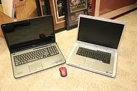 Two Dell laptops placed side by side on floor with a wireless mouse in front