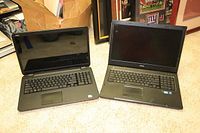 Two Dell laptops side by side on carpeted floor