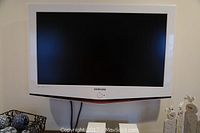 Front view of Samsung white flatscreen TV with power button and logo visible.