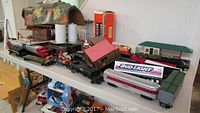 Overview on table showing assorted Lionel train cars, track box, mountain tunnel, station and accessories