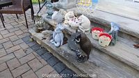 Overview of garden decor assortment arranged on and around stone stairs, showing different animal statues and pots