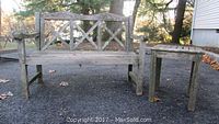 Photo of weathered teak bench and matching side table outdoors on gravel with trees in background. Shows overall view and condition of both pieces.