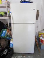 Front view of white Frigidaire top freezer refrigerator showing two doors and exterior condition.