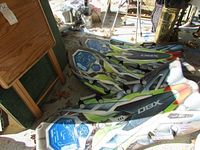 Three DBX plastic foam sleds stacked on the floor in a room. Visible graphics in blue, green, and red with a black DBX logo.