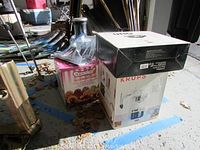Photo showing boxes of Krups Espresso Mini, Danvier Premier frozen dessert maker, and other kitchen items grouped together on the floor.