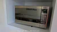 Panasonic NN-SN671S microwave oven in built-in kitchen shelf, stainless steel finish.