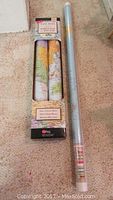 Four rolled wall maps in original packaging on carpeted floor; packaging states 'Peel, Stick & Move Won't Harm Walls, Movable/Reusable','GeoNova' brand visible.