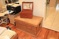 Photo of large wooden trunk with metal handles and handmade wooden jewelry box on top.
